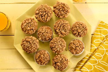banana nut muffins on a yellow platter, with yellow napkins, a yellow tabletop and orange juice 
