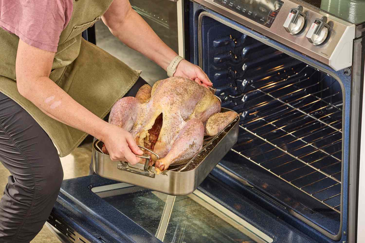 A person putting a Grassland Beef Pasture Raised Turkey into an oven