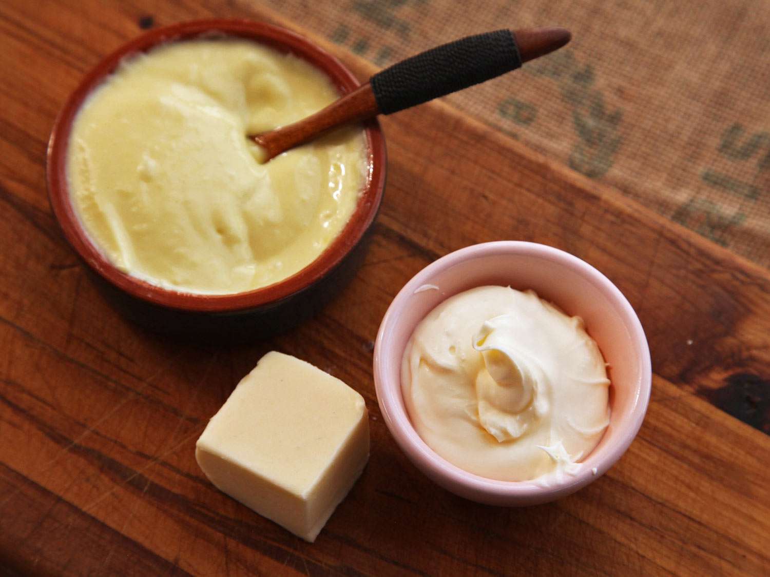 Enriching ingredients to choose from, arranged on a cutting board: a knob of cultured butter, a prep bowl of homemade mayonnaise, and a ramekin of crème fraîche.