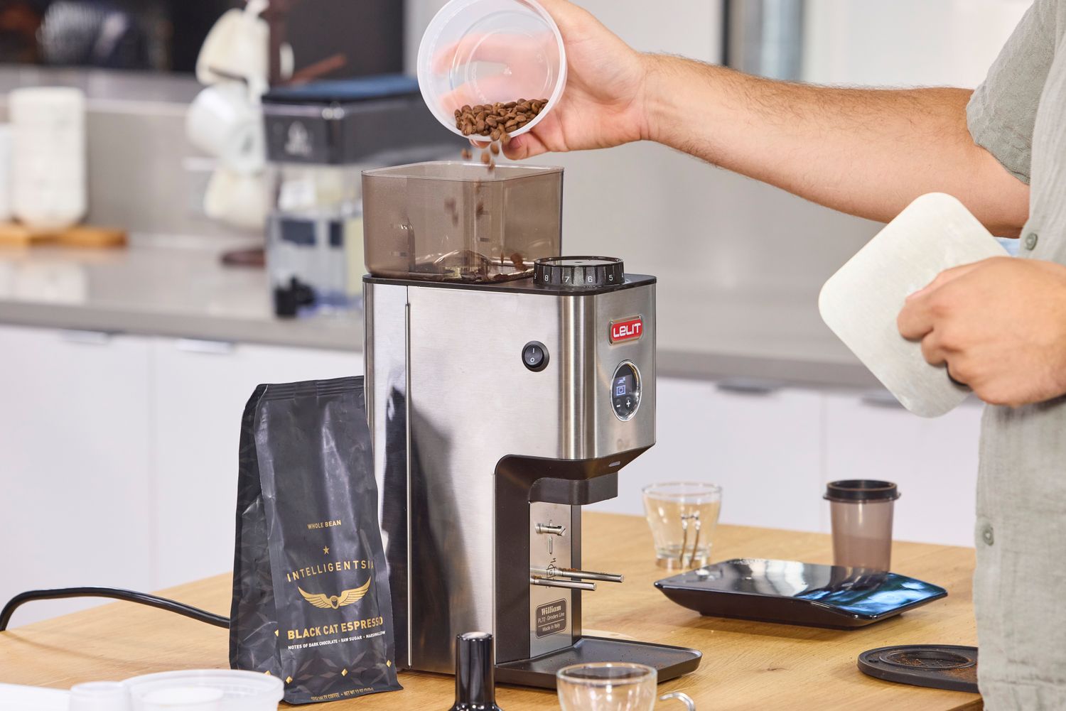 A person pours coffee beans into the Lelit William Espresso Grinder
