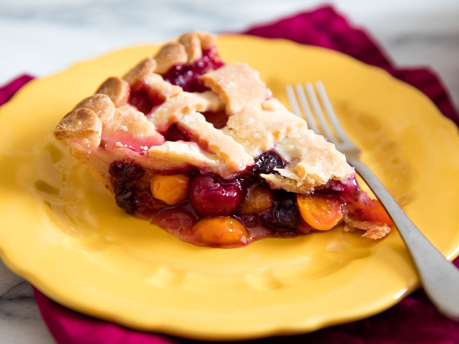 A slice of cherry pie with a lattice crust, made with gluten-free pie crust, on a yellow plate
