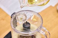 A person pours oil into the KitchenAid Go Cordless 5-Cup Food Chopper