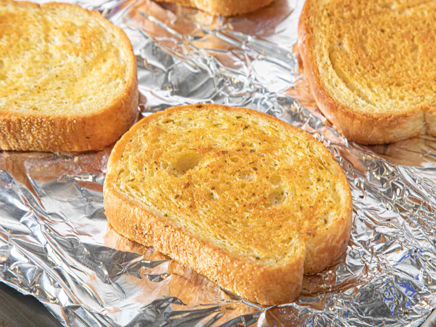 Slices of garlic bread on aluminum foil