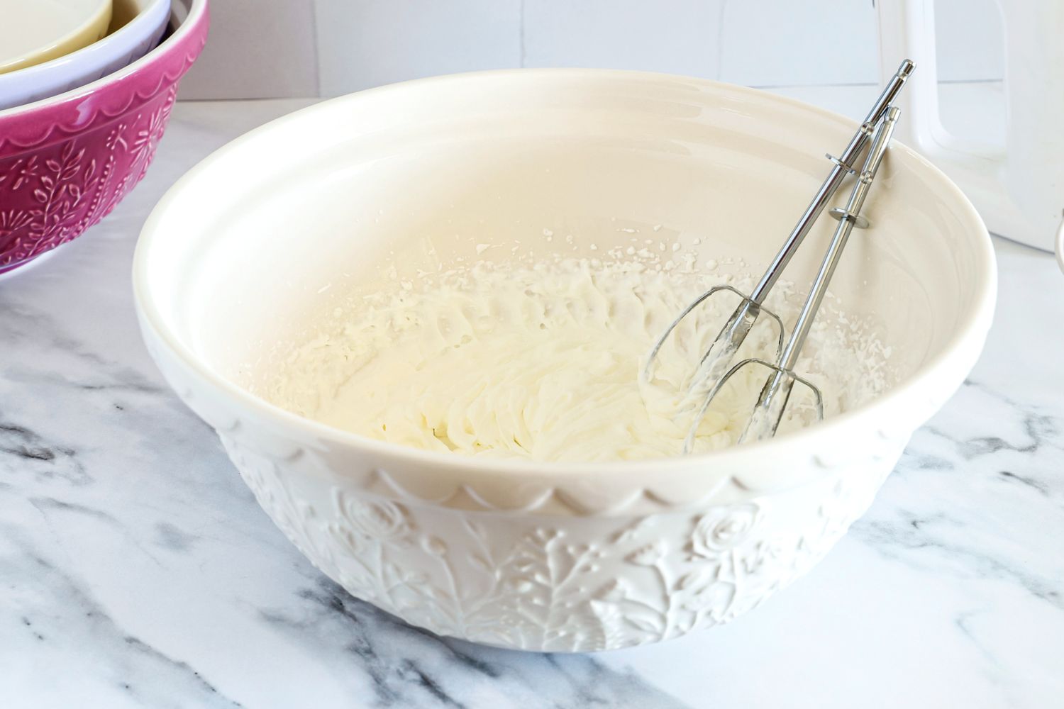 Creamy mixture in a Mason Cash bowl with a hand mixer