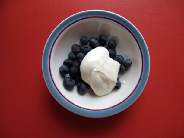Overhead shot of a bowl of blueberries dolloped with crème fraîche