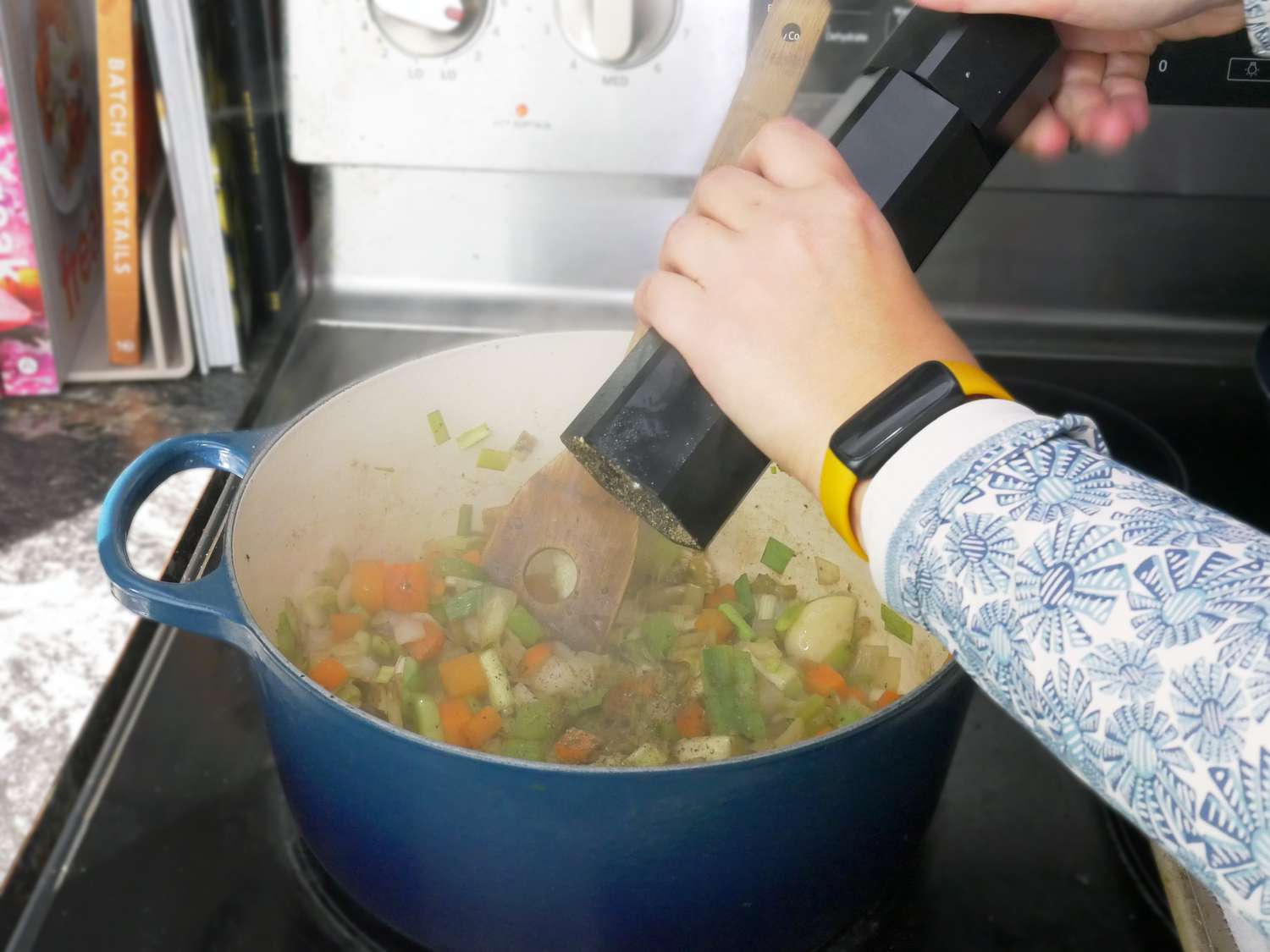 a person using the hexill to season mirepoix in a dutch oven