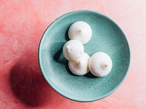 aquafaba-cardamom meringue cookies on a blue plate on a pink background