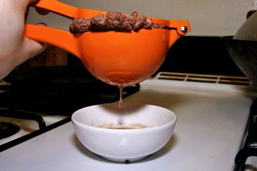Squeezing a fully cooked hamburger in a citrus juicer, showing all of the juice that comes out.