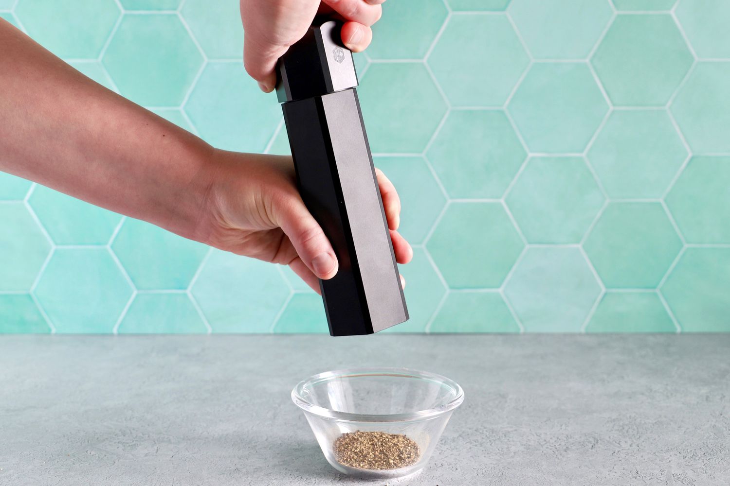 a person using the hexclad pepper mill to grind pepper