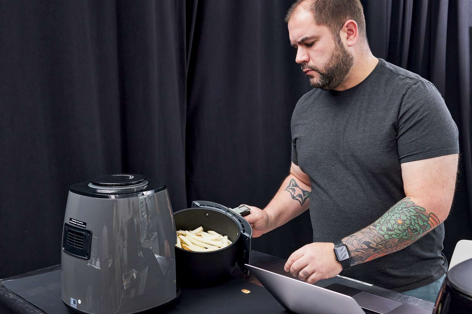 A person placing a basket of fries into a Ninja air fryer.