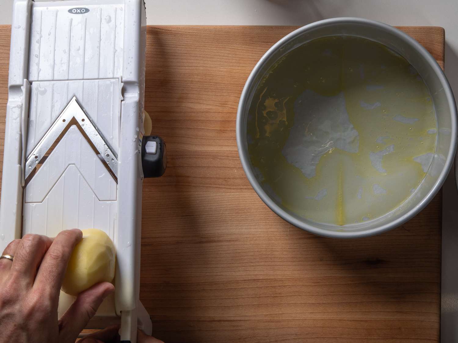Slicing the potatoes on a mandoline to make perfect 1mm thick slices.