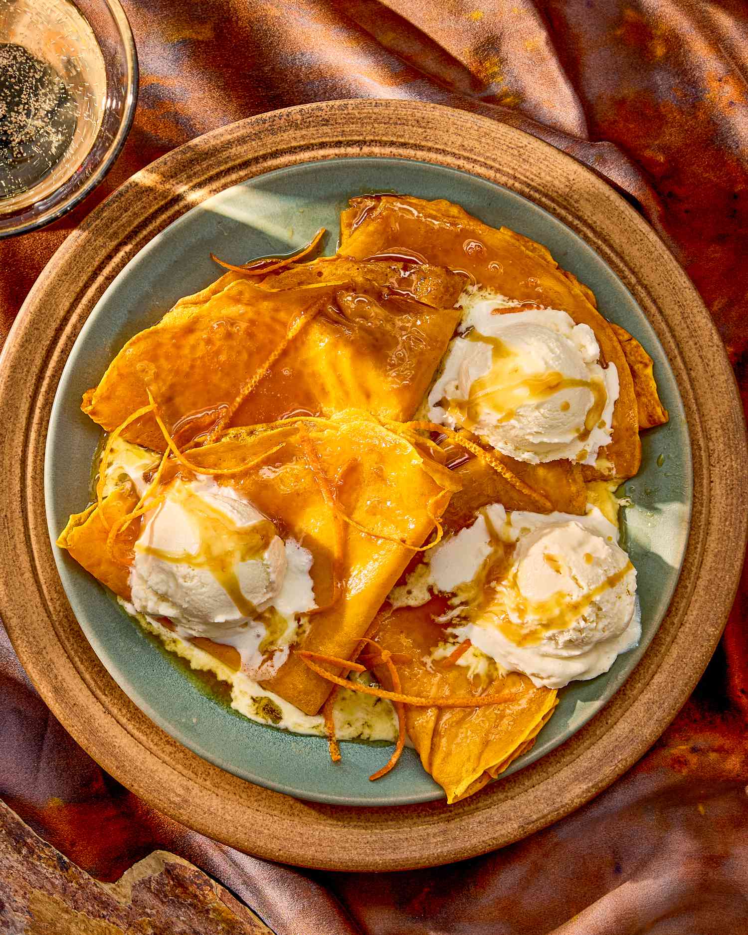 A plate of crepes topped with scoops of cream and drizzled with syrup