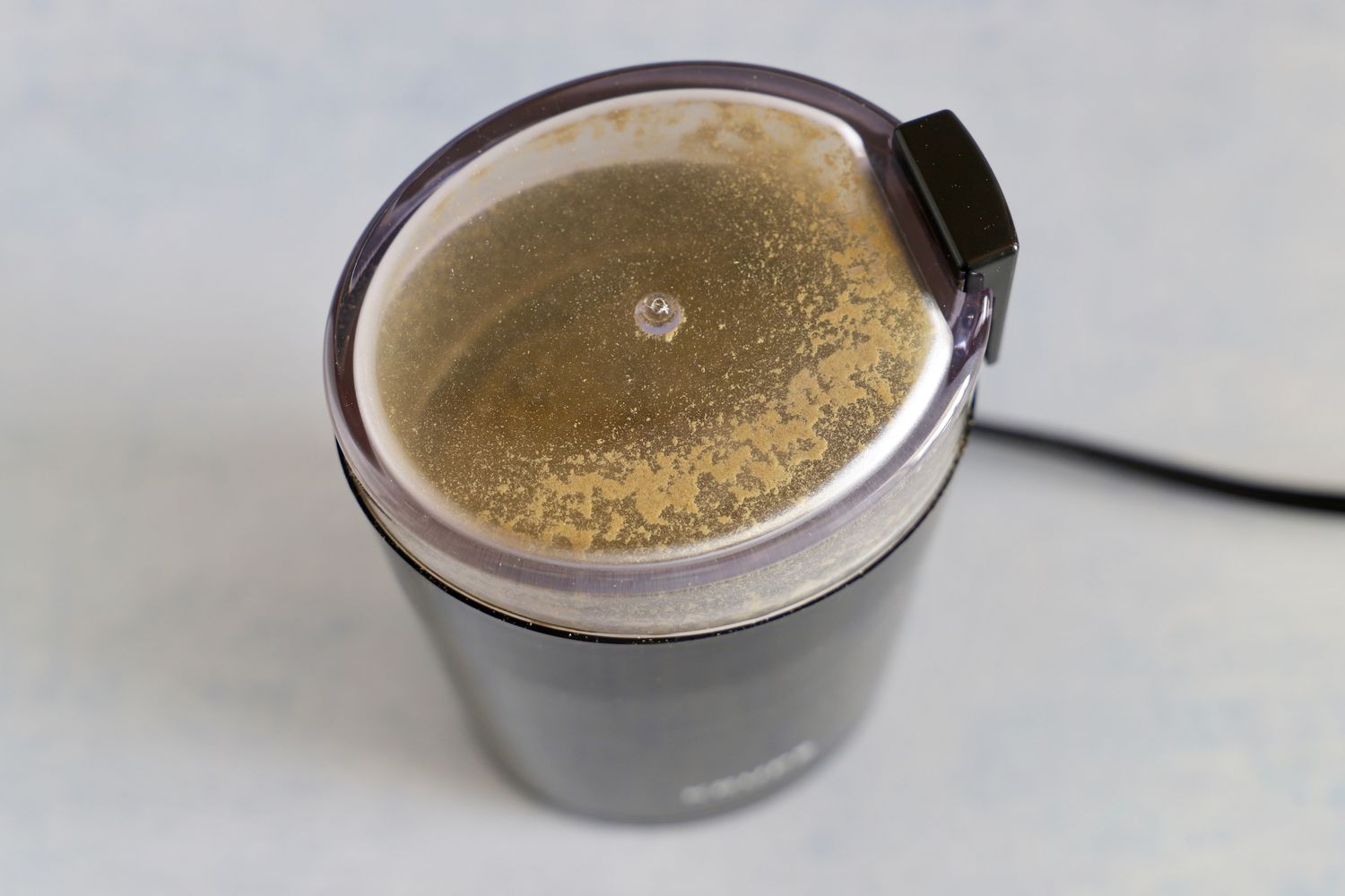 the krups spice grinder with bits of spice on the lid interior