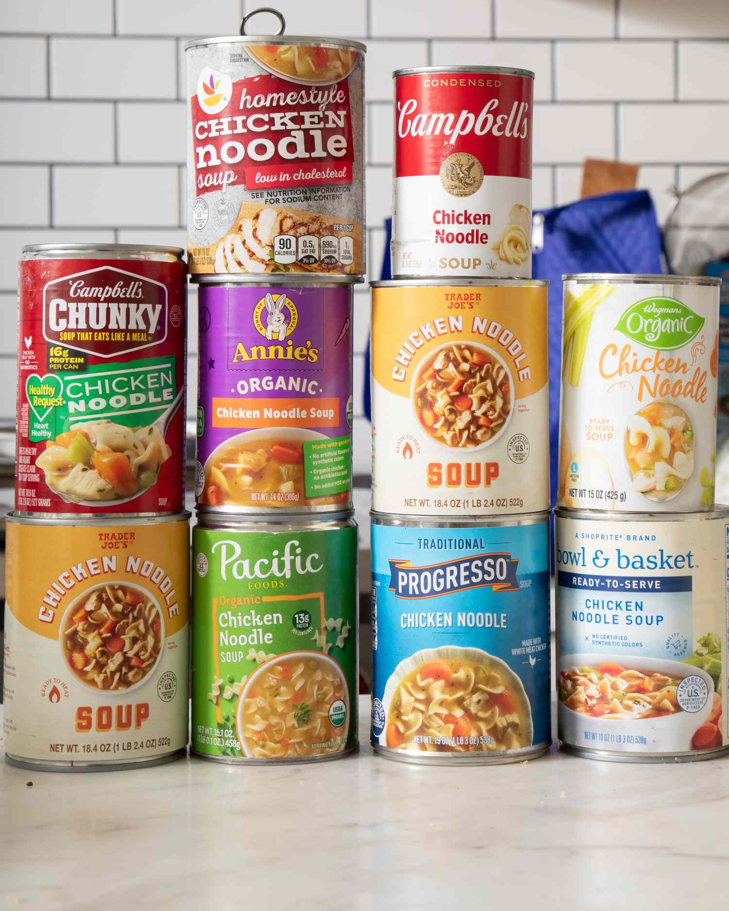 Cans of various chicken noodle soup brands arranged on a kitchen counter