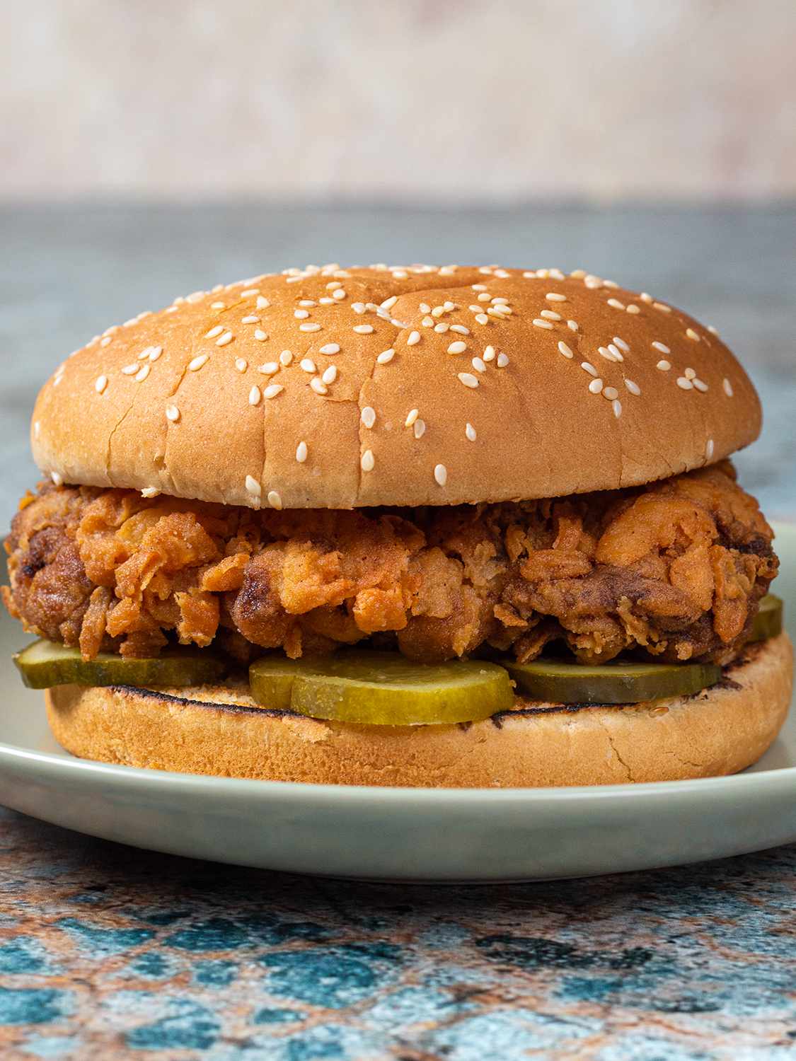 A fried chicken sandwich on a blue ceramic plate.