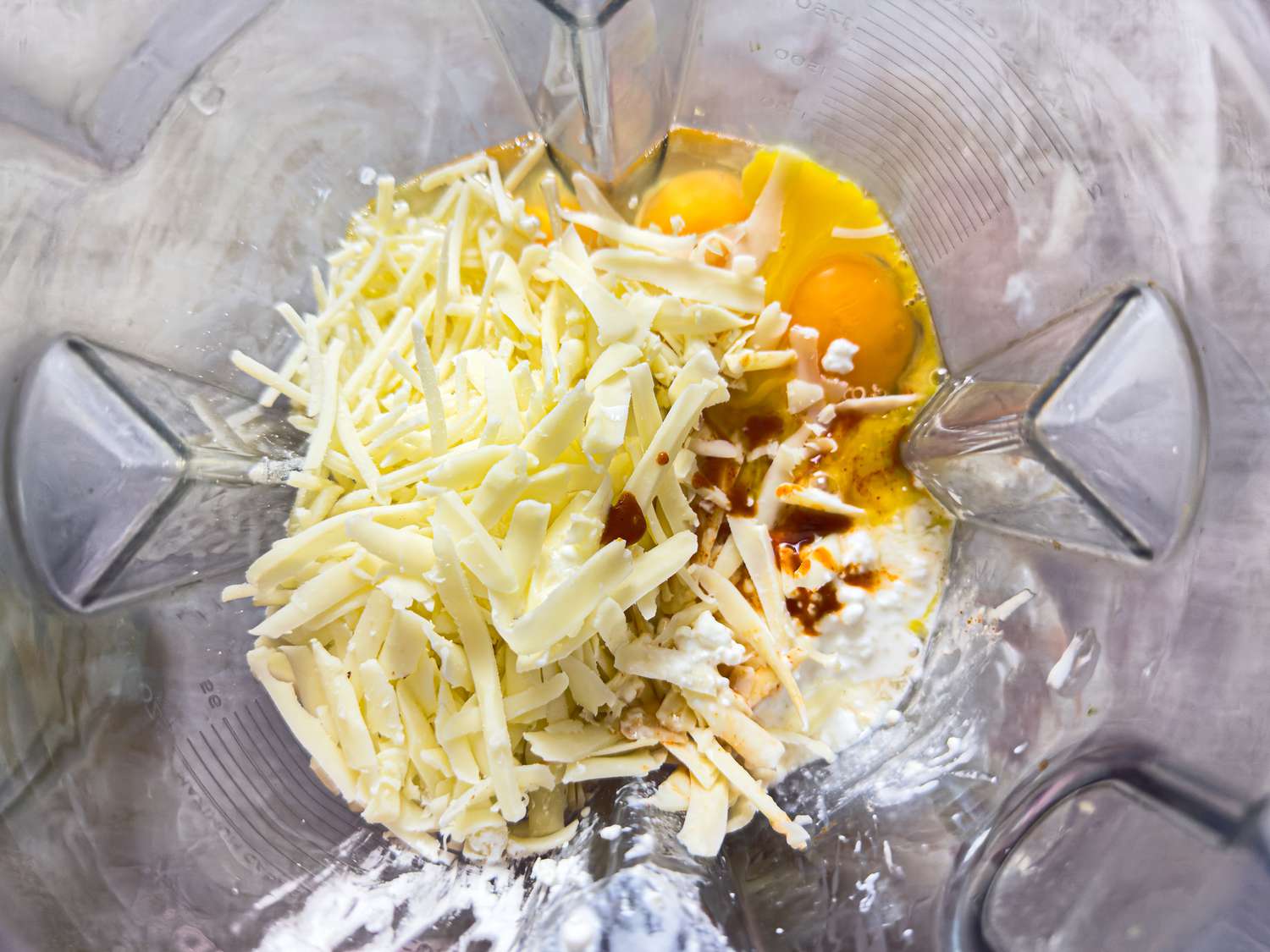 Ingredients in a blender including shredded cheese and eggs