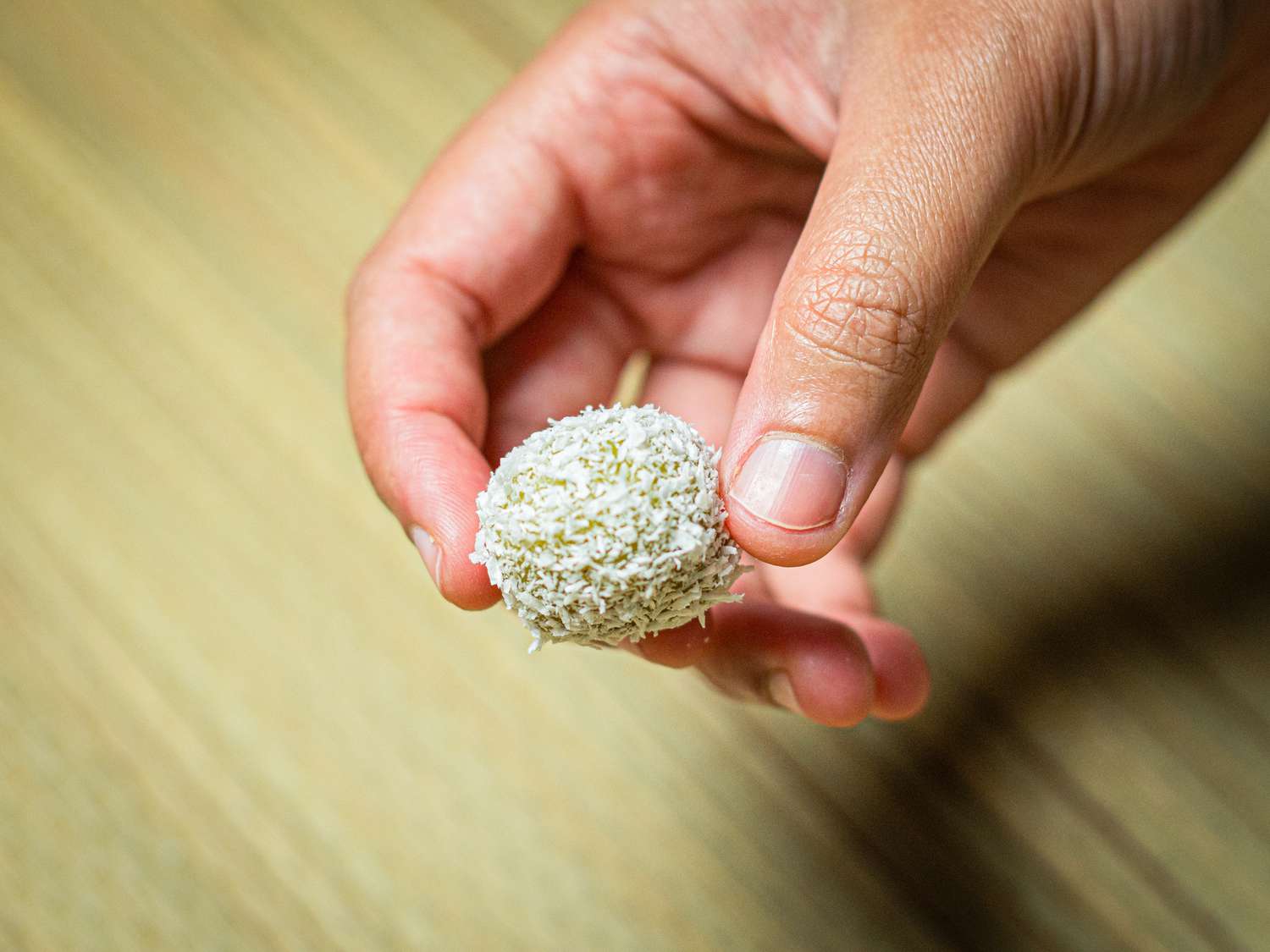 Overhead view of a hand holding a single onde-onde