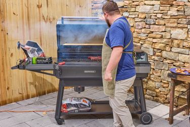 Person grilling meat on a large barbecue grill outdoors