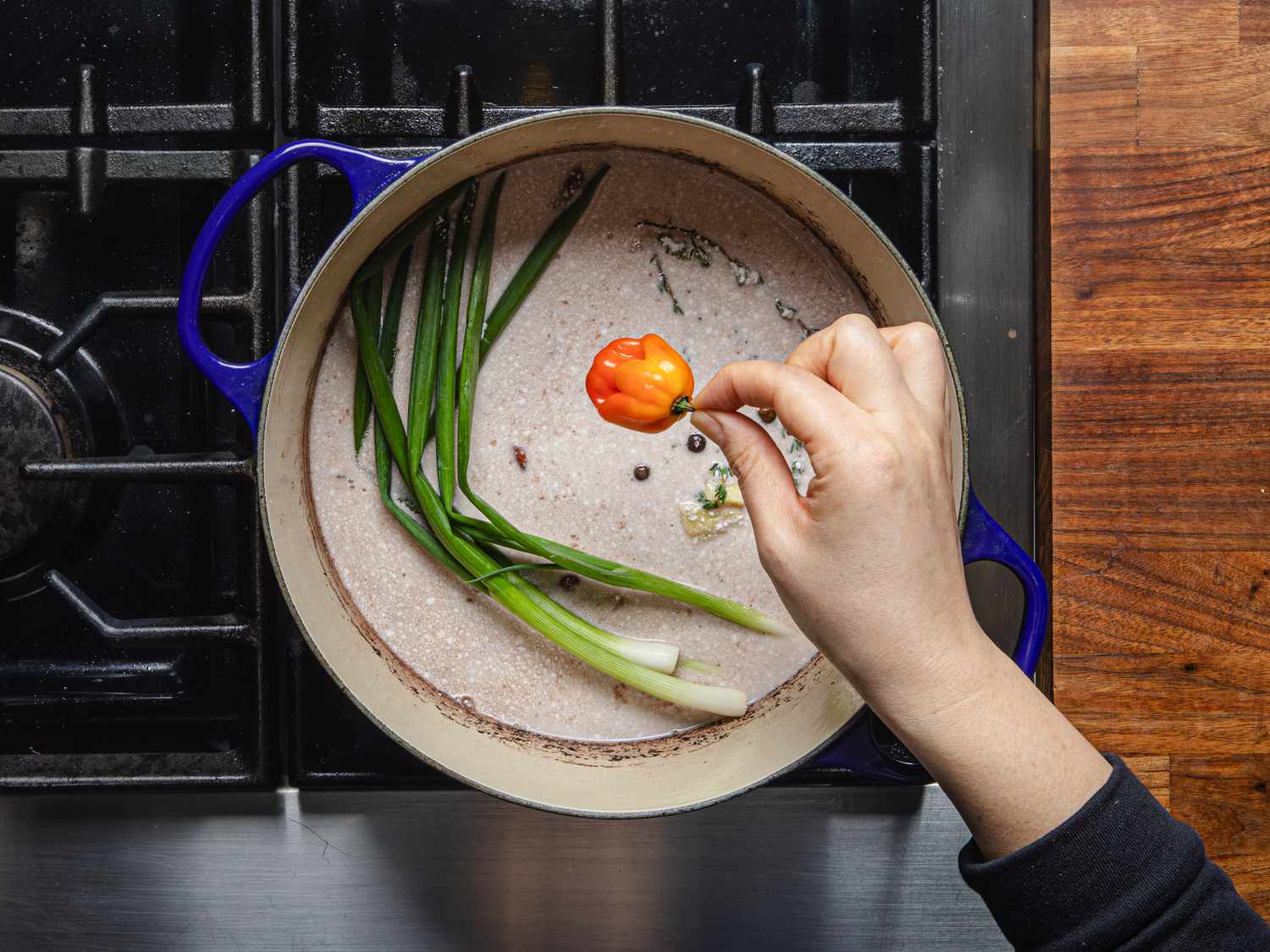 Overhead view of scotch bonnet being added to pot