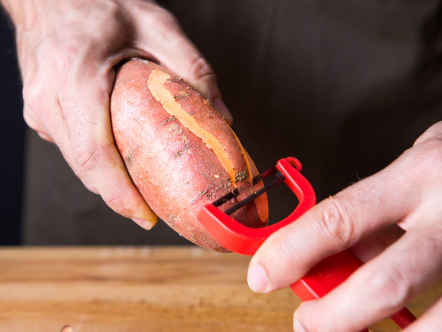 A y-peeler being used on a sweet potato