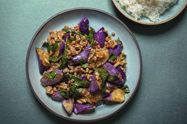 Overhead view of eggplant stir-fry plated on a blue plate on a blue background