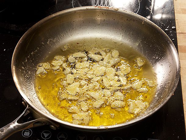 A large quantity of sliced garlic frying in olive oil for Spanish-style garlic shrimp.