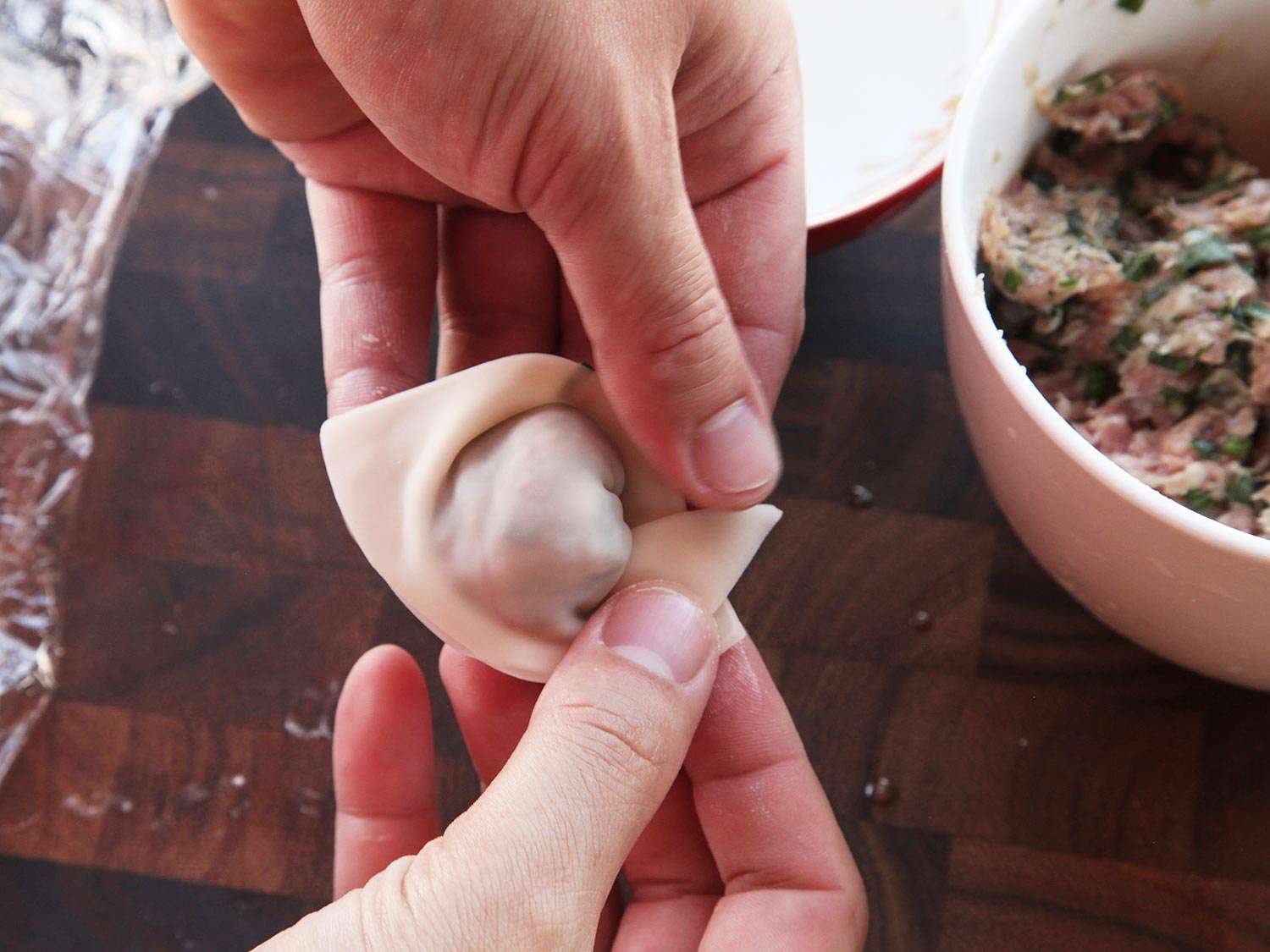 Crossing the arms of a filled wonton triangle to make the classic "folded arms" shape. 