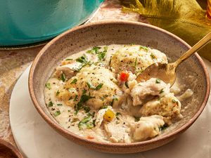 Chicken dumpling soup in a bowl with a spoon garnished with parsley
