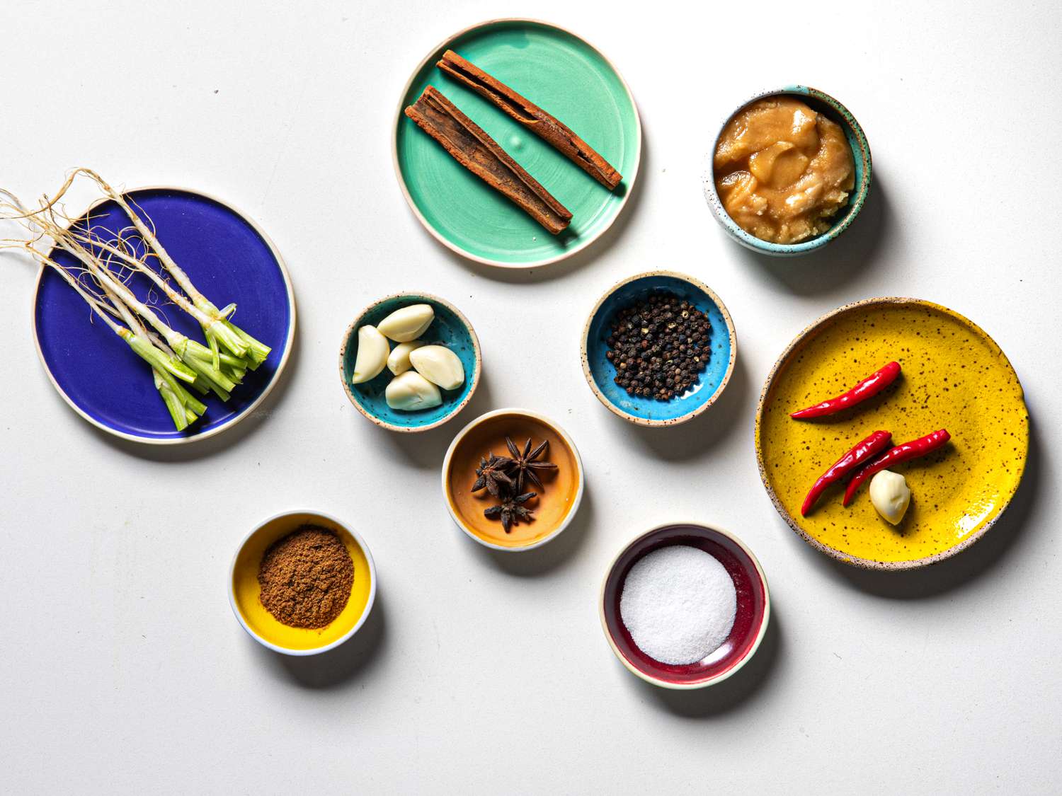 Mis en place of ingredients for stew on brightly colored plates of various sizes