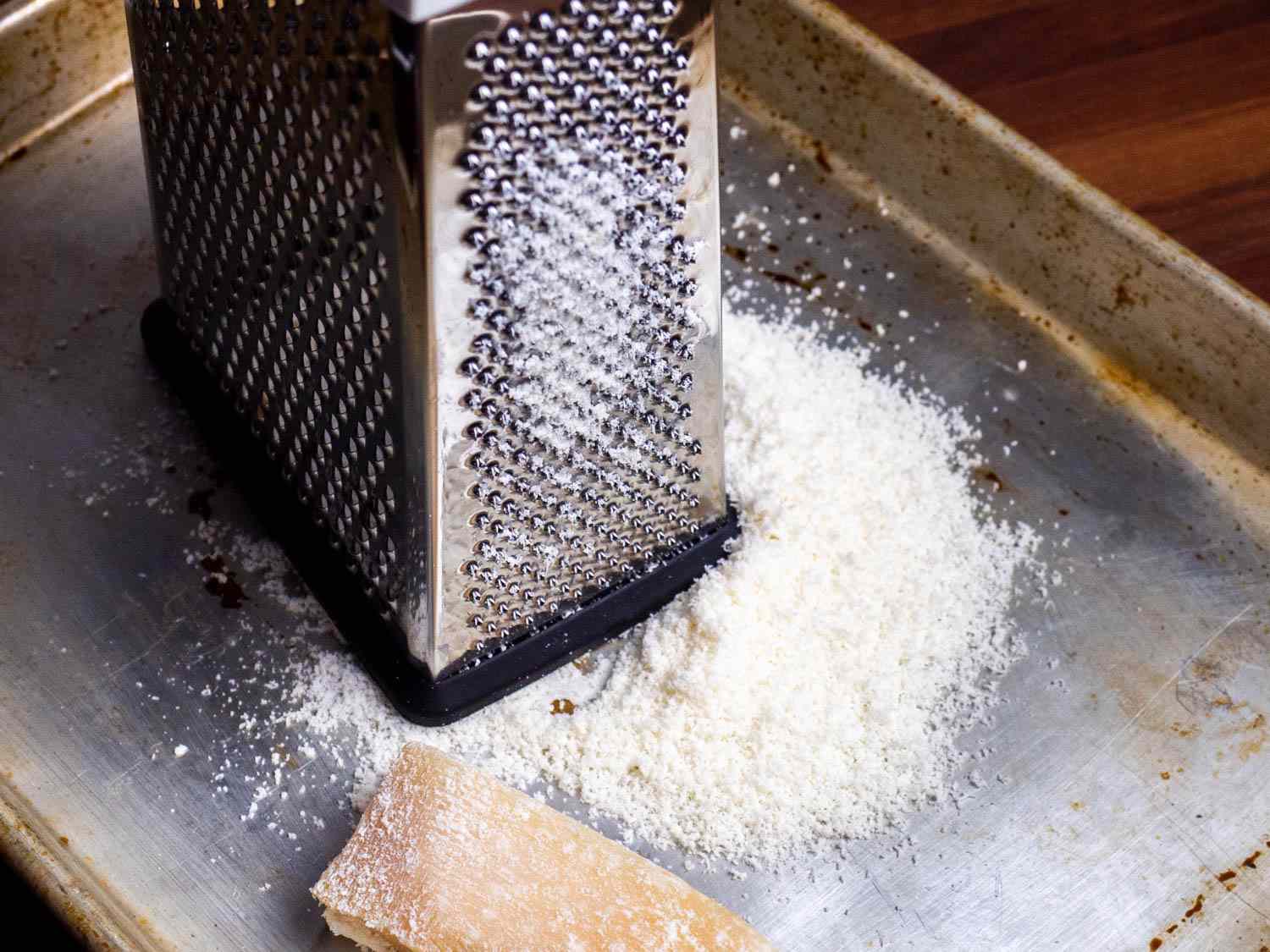A box grater with a pile of finely grated Parmesan next to it