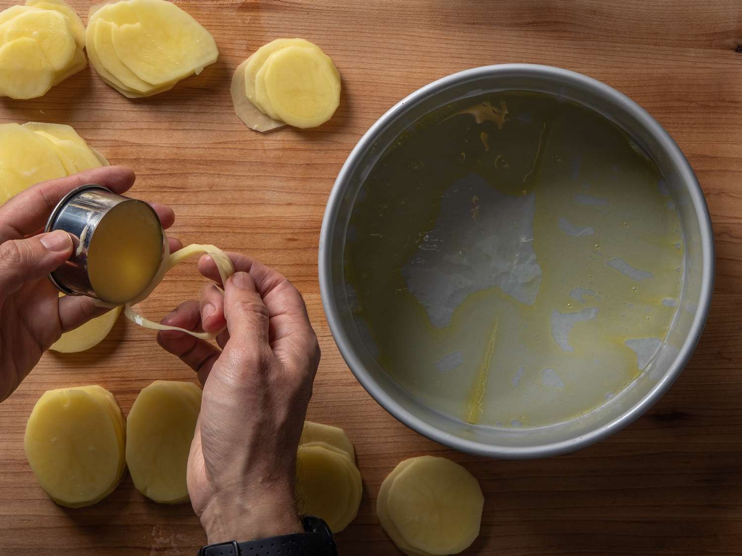 Stamping thin potato slices into perfect rounds using a round cookie cutter