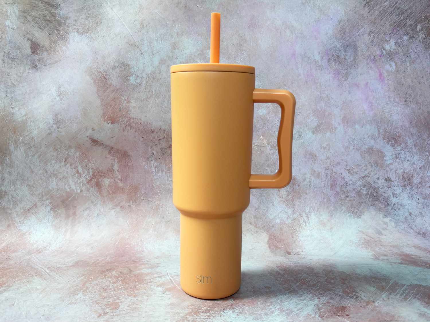 An orange insulated tumbler on a countertop.
