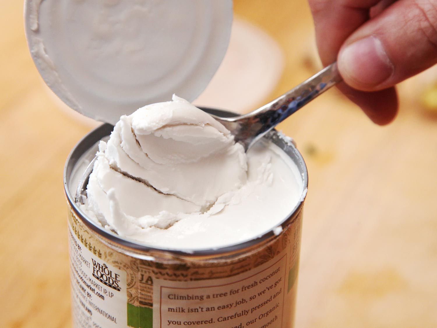 Scooping separated cream from can of coconut milk for peanut soup. 