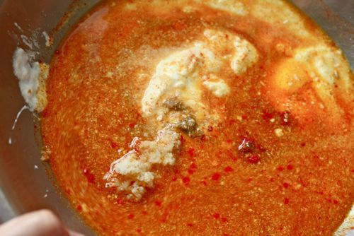 Close-up of a bowl containing the marinade ingredients, ready to be mixed. Achiote paste lends it a deep red hue.