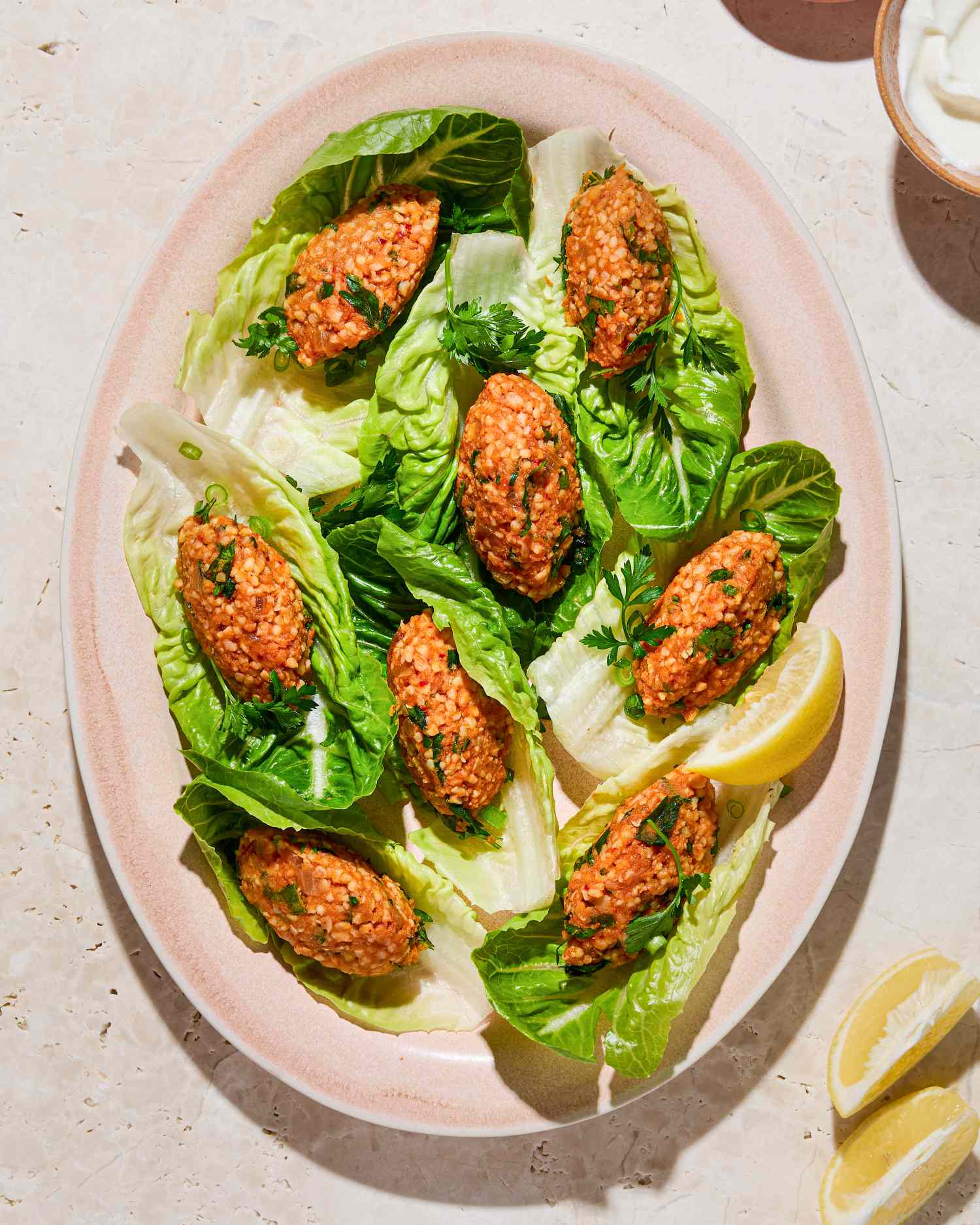 Platter of Turkish lentil kofte served on lettuce leaves with lemon wedges
