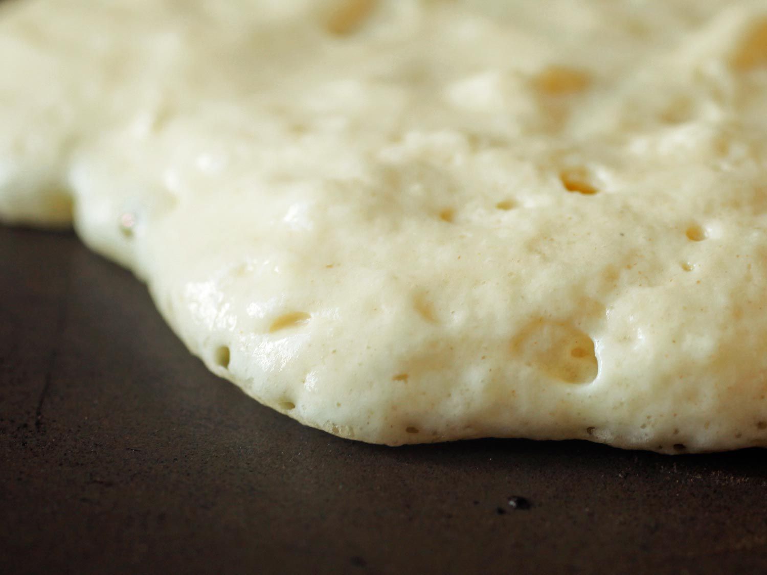 Closeup of pancake batter forming small air bubbles as it cooks