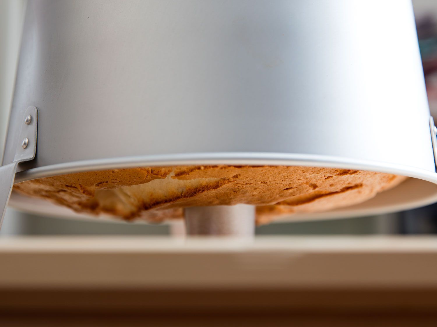 Angel food cake cooling upside down inside a tube pan.