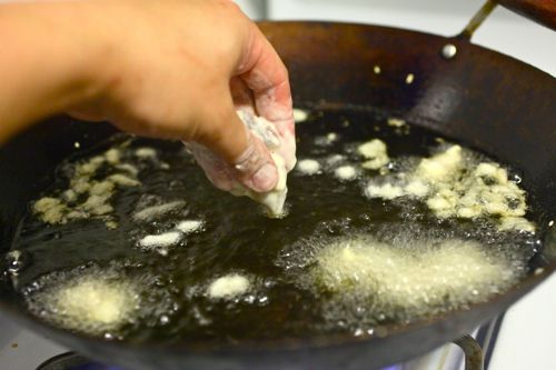 Dropping battered food into oil in a wok.