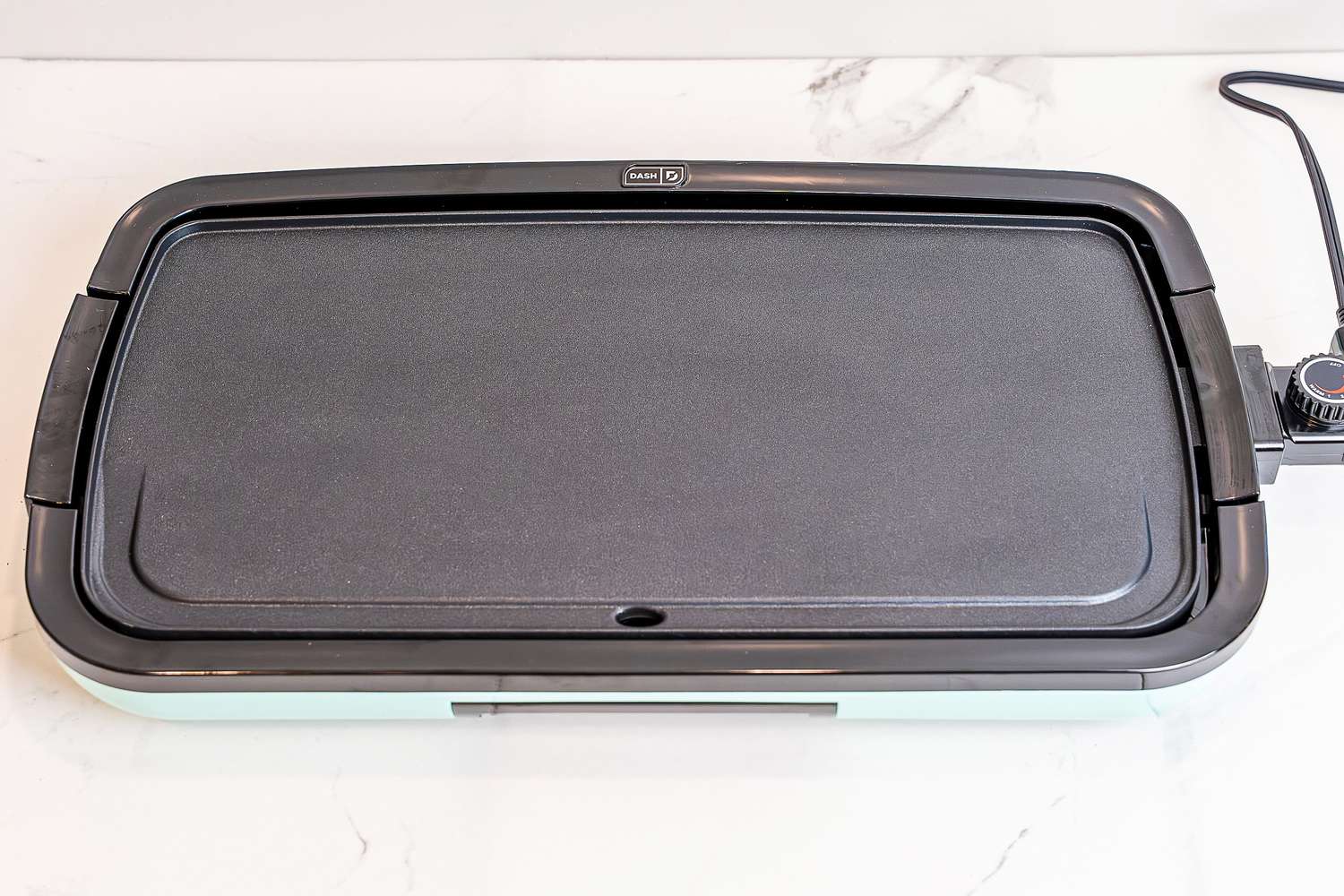 The Dash electric griddle on a white marble countertop