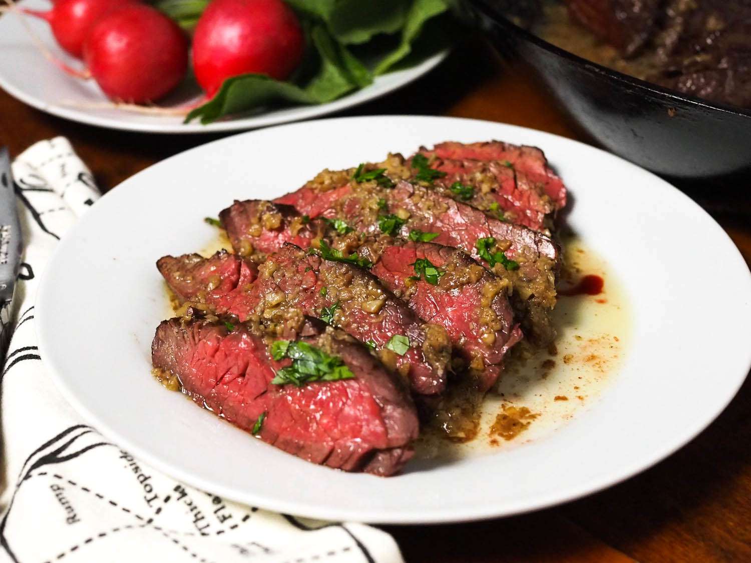 Slices of medium-rare hanger steak with bagna cauda pan sauce on a plate.
