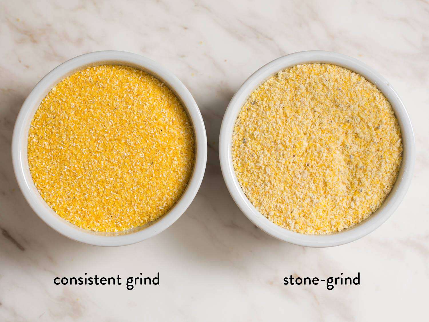 A comparison of consistent grind and stone-grind polenta in small white ramekins. The stone-ground on the right is more varied in size and color.