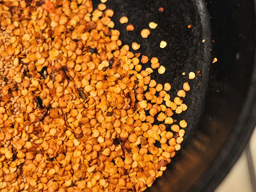 Overhead of chile seeds cooking in a skillet.