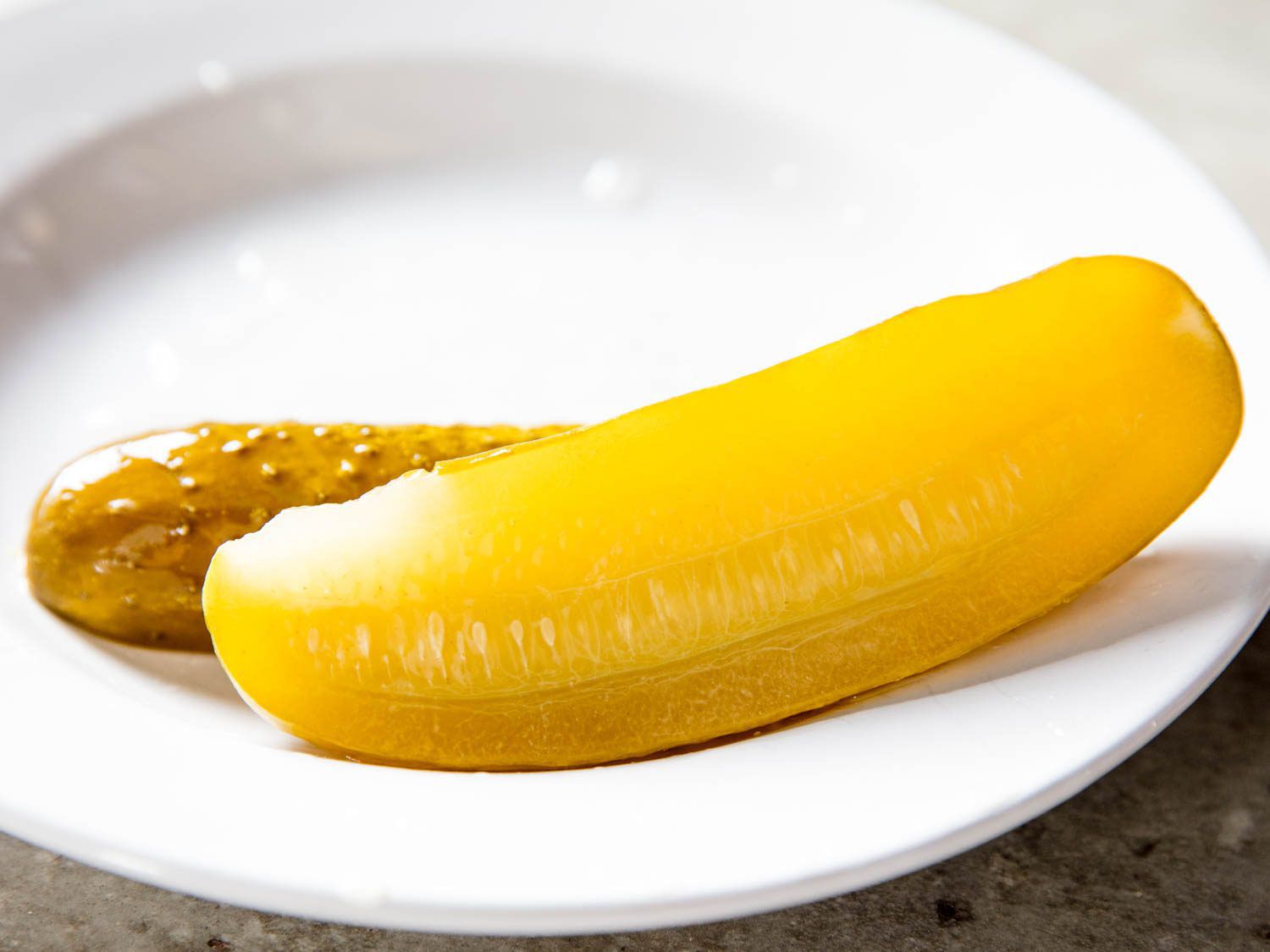 Pickled cucumber sliced in half, resting on a plate