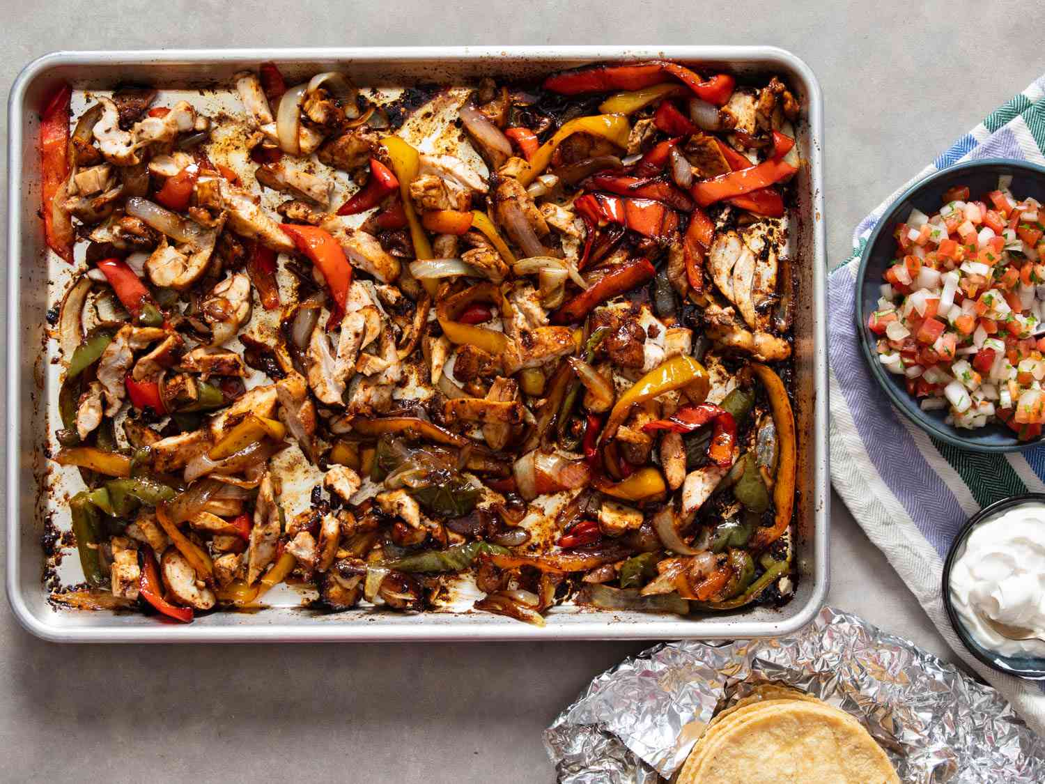 Sheet pan chicken fajitas with pico de gallo and tortillas.
