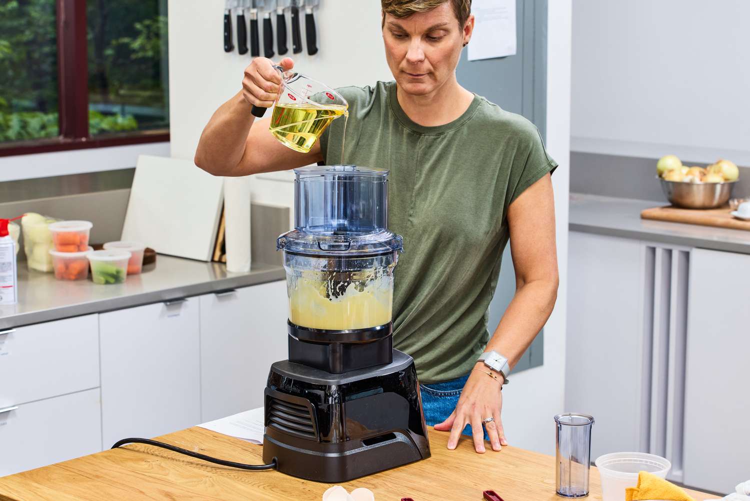 A person pours liquid into the Vitamix 12-Cup Food Processor Attachment