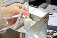 Closeup of a hand holding a tube attached to the Lelit Elizabeth Espresso Machine