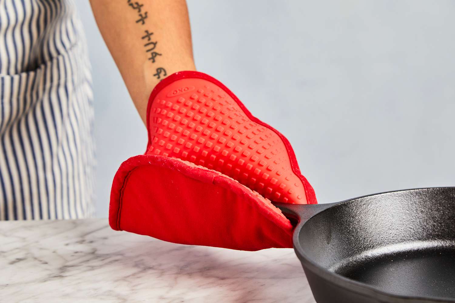 a pot holder being used to hold the handle on a cast iron skillet