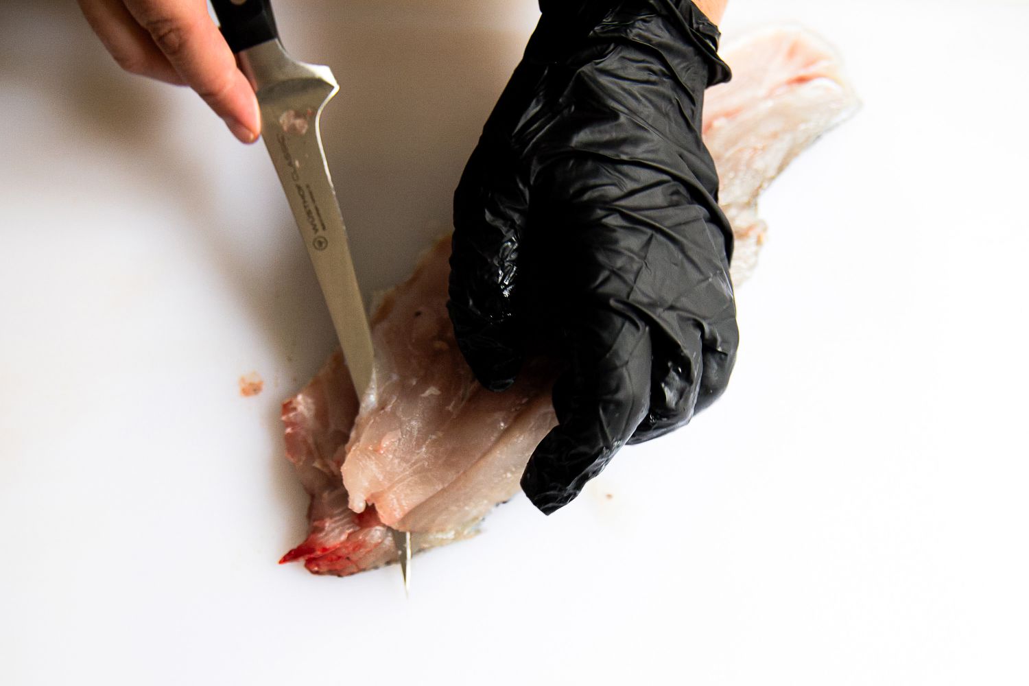 A person using the Wüsthof Classic Fish Fillet Knife to cut a fish