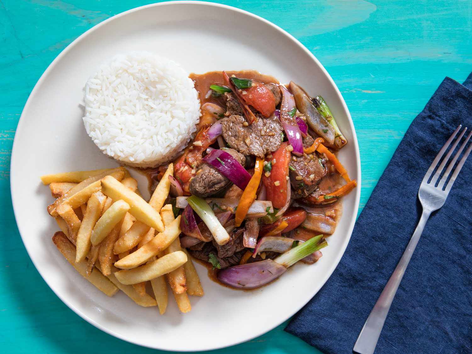 Overhead view of lomo saltado plated with french fries and white rice.