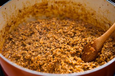 Pot of ragù bolognese with a wooden spoon